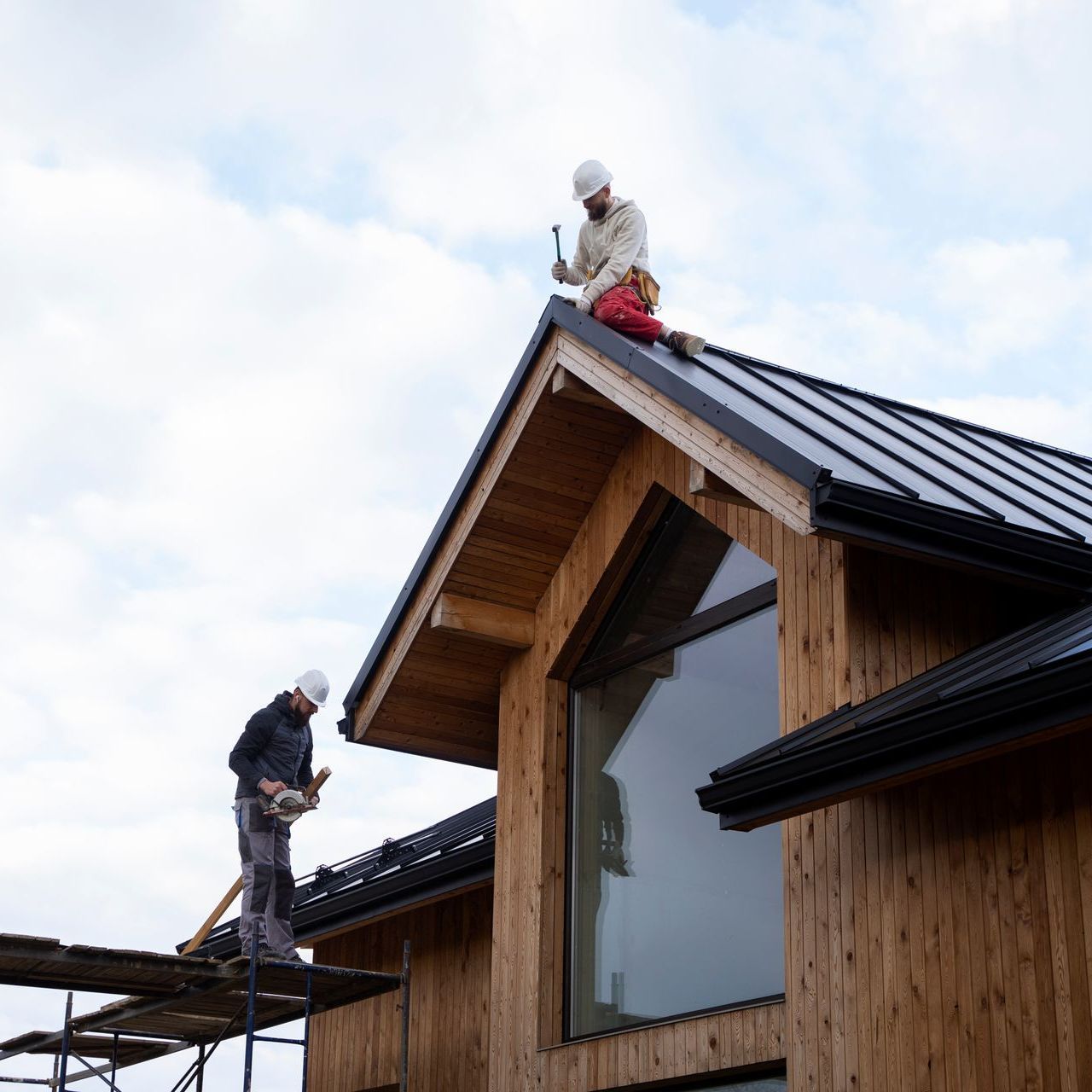 two men are working on the roof of a wooden house