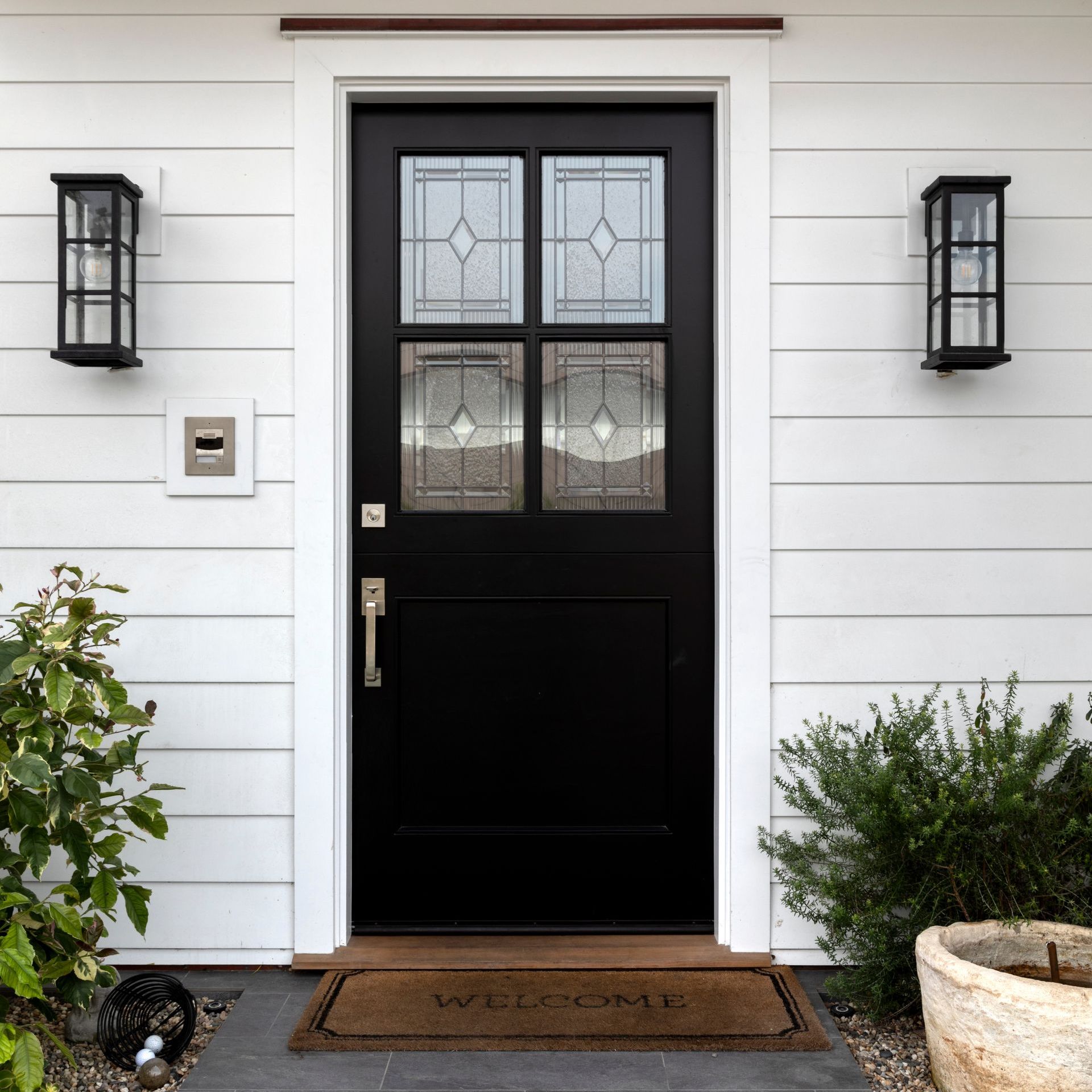a black door with a welcome mat in front of it