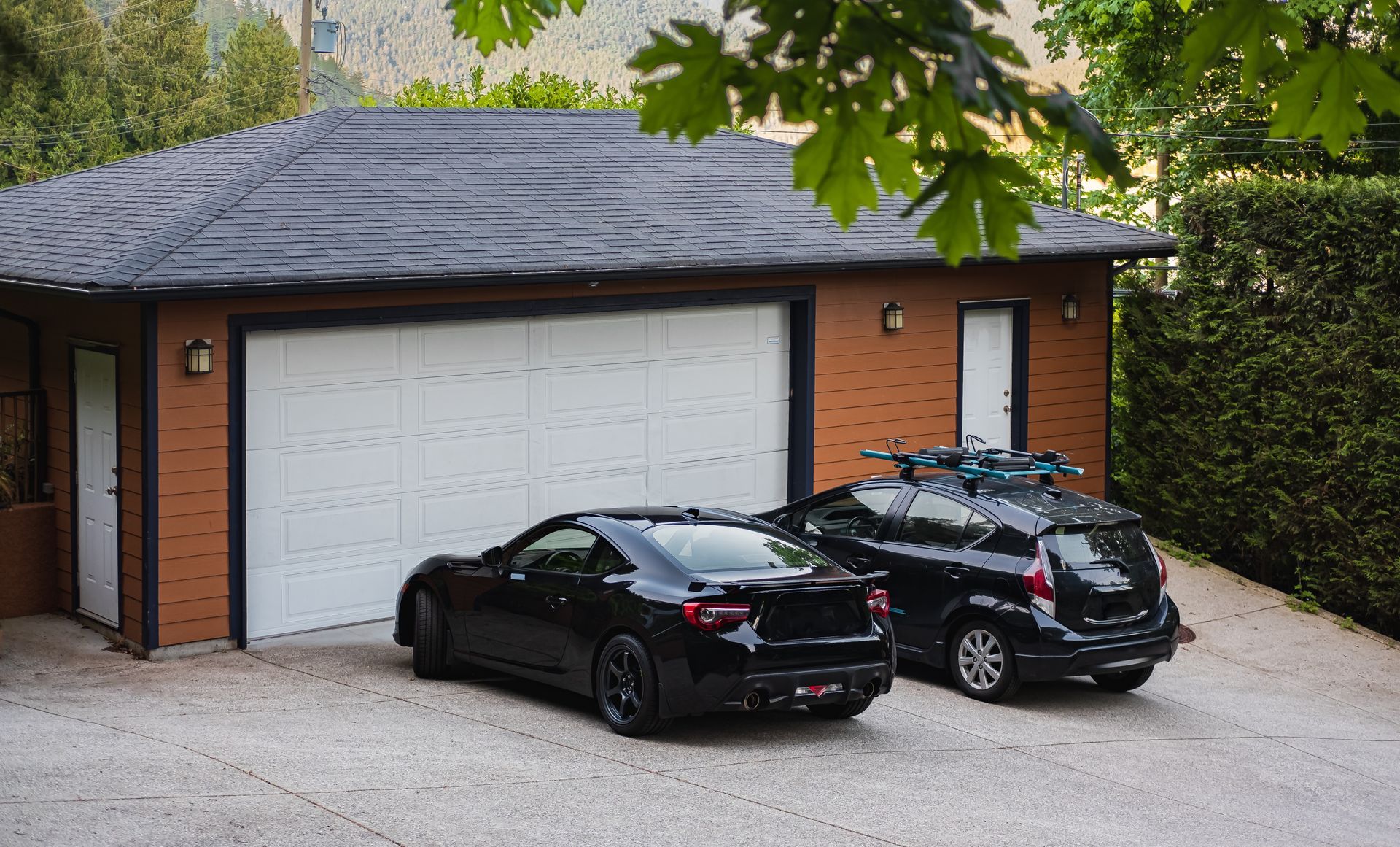 two black cars are parked in front of a garage