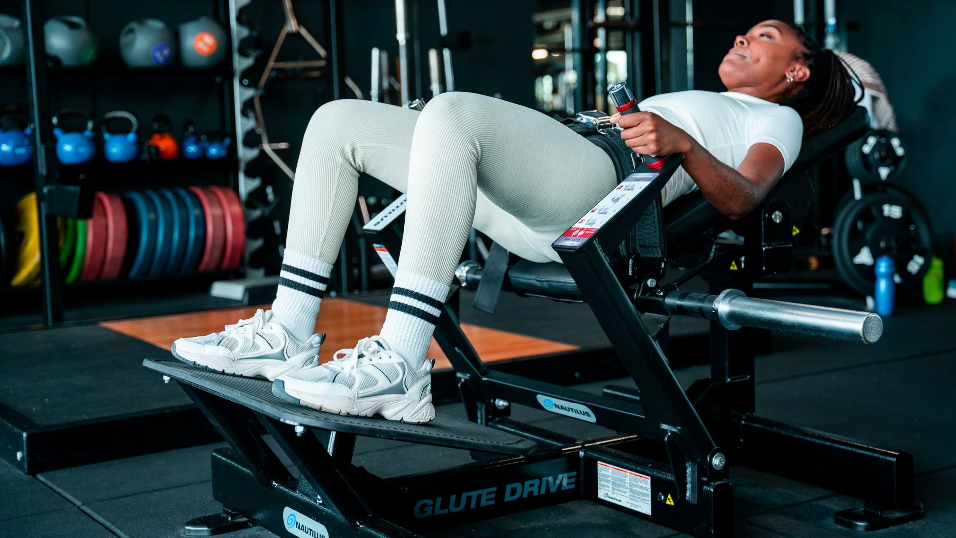 Een vrouw doet squats op een machine in een sportschool.