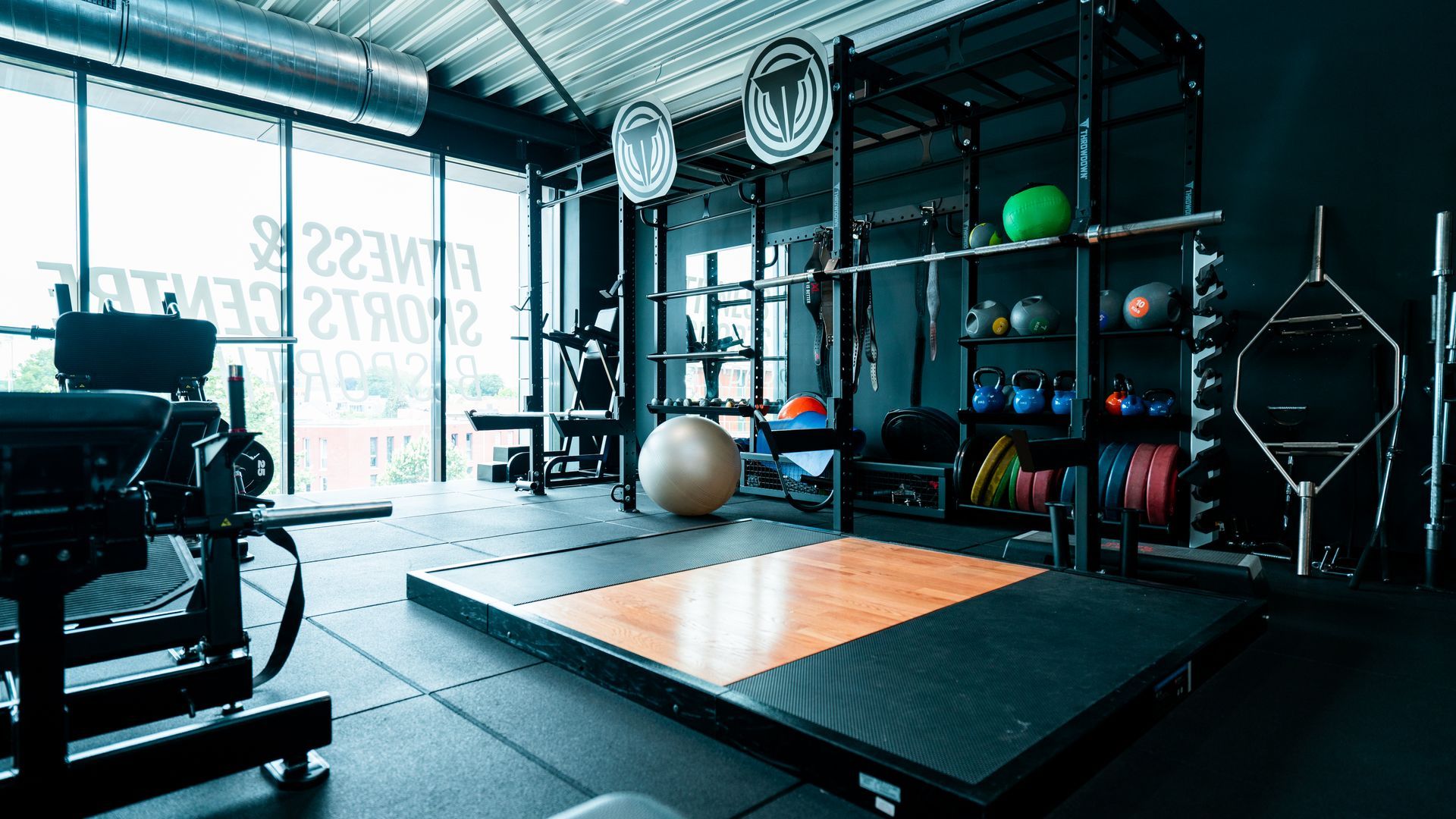 Een fitnessruimte met een houten platform in het midden van de kamer.