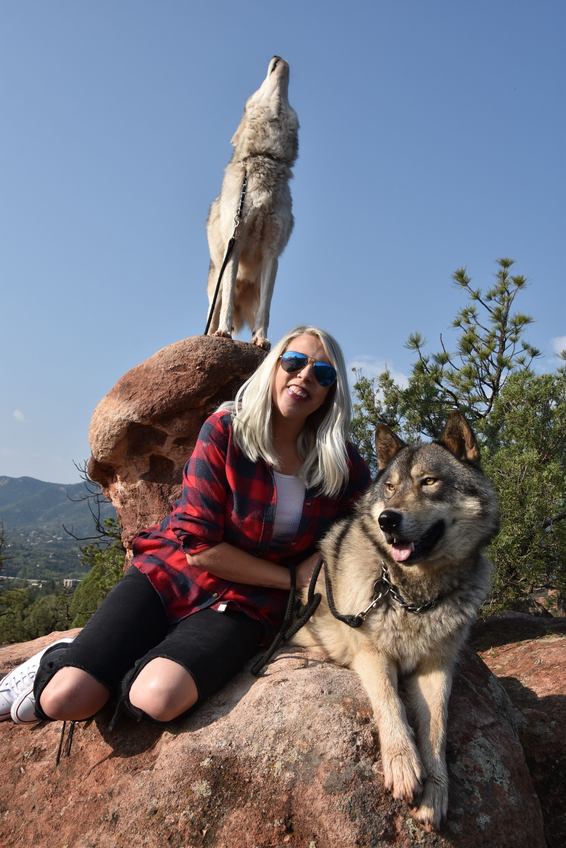 a woman wearing a hat and sunglasses stands in front of a wall