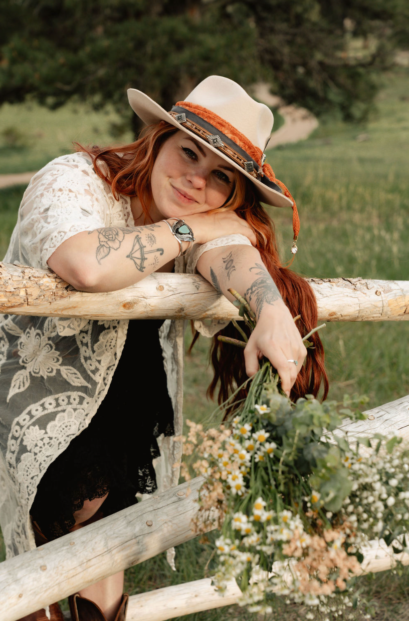 a woman wearing a hat and sunglasses stands in front of a wall