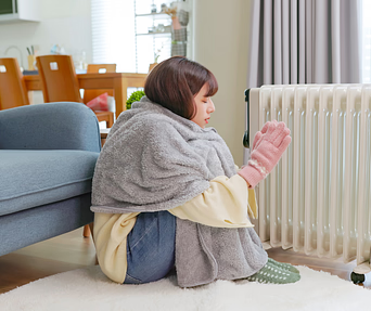 A woman is sitting on the floor in front of a radiator.