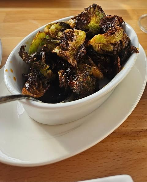 A bowl of crispy brussel sprouts with a spoon in it