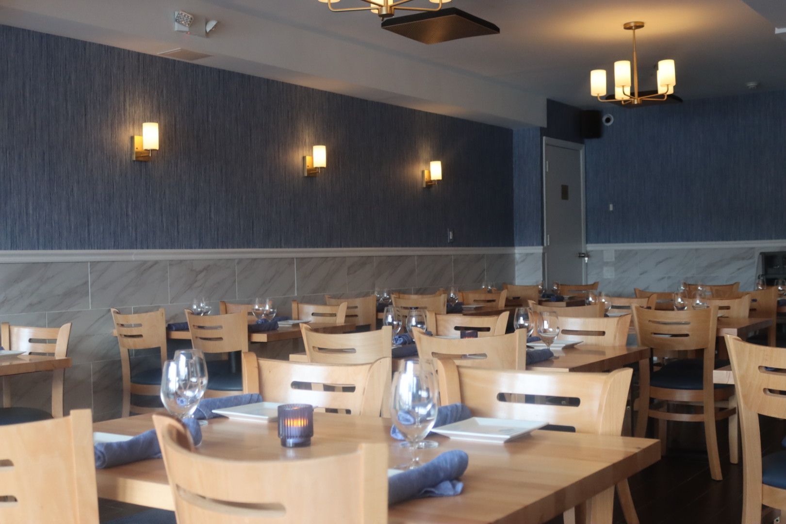Inside of Drift Seafood restaurant with tables and chairs and a chandelier