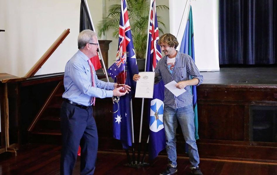 Man in Suit Presents a Document to a Young Man on a Stage — Immigration Agents in Cairns North, QLD