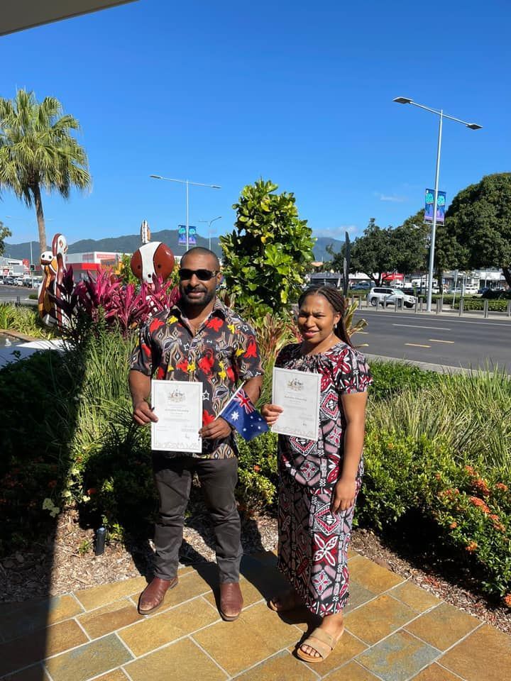 Two People Holding Documents, an Australian Flag, Smiling — Immigration Agents in Cairns North, QLD