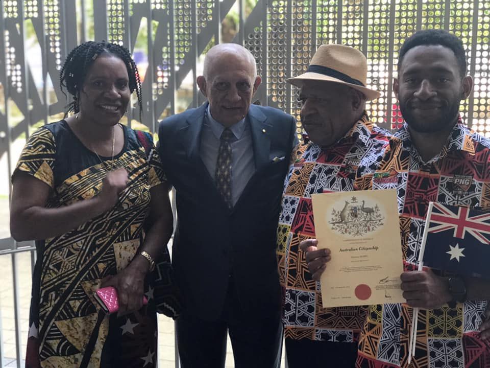 Four People Pose, Holding an Australian Citizenship Certificate and Flag — Immigration Agents in Cairns North, QLD