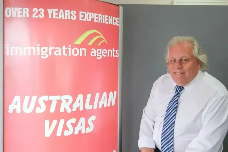 Man in White Shirt and Tie Stands Next to a Sign for Australian Visas — Immigration Agents in Cairns North, QLD