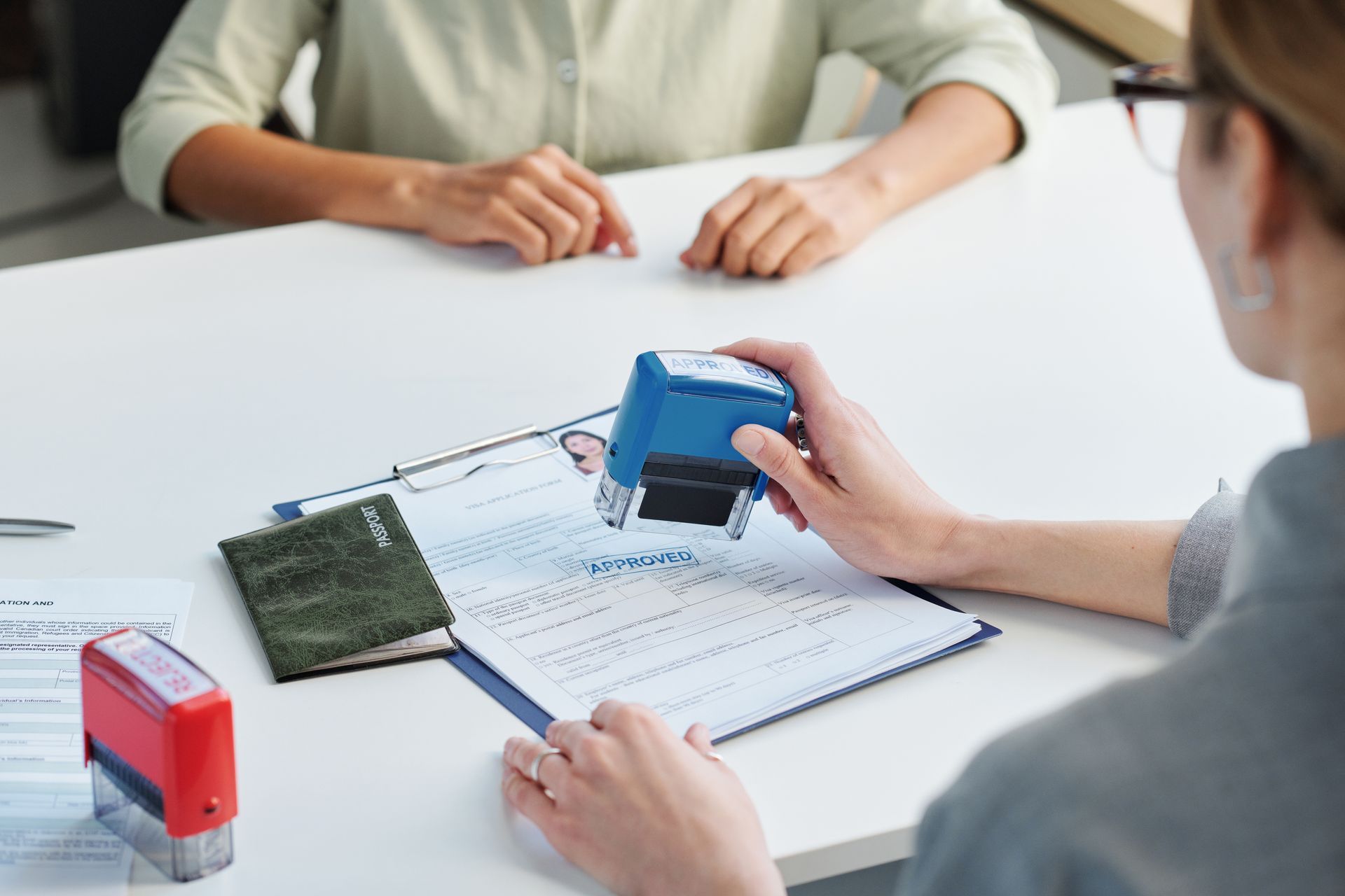 A Person Stamping a Document on a Desk, Near a Passport — Immigration Agents in Cairns North, QLD