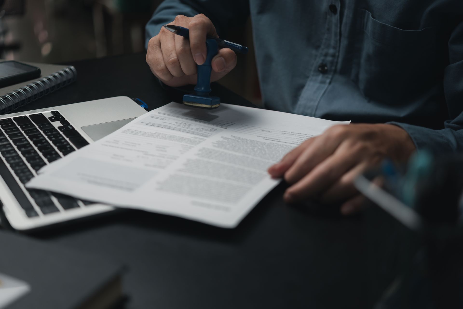 Person Stamps a Document on a Desk With a Laptop — Immigration Agents in Cairns North, QLD