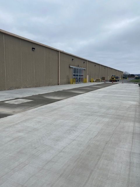 A Large Building With A Concrete Driveway — Rome, NY — EWS Sealcoating