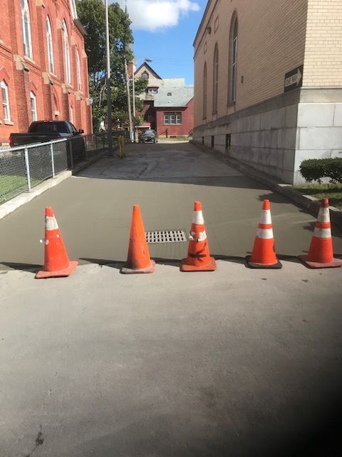 A Row Of Orange And White Traffic Cones On The Side Of A Road — Rome, NY — EWS Sealcoating