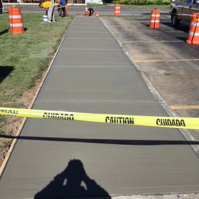A Concrete Walkway With A Yellow Caution Tape — Rome, NY — EWS Sealcoating
