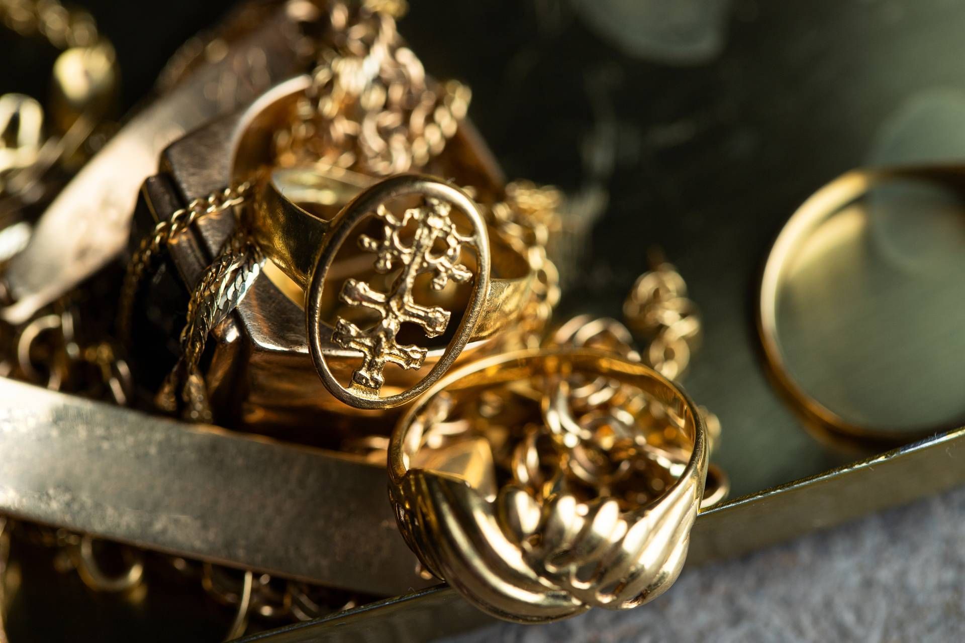 Gold rings and chains displayed on a gold surface.