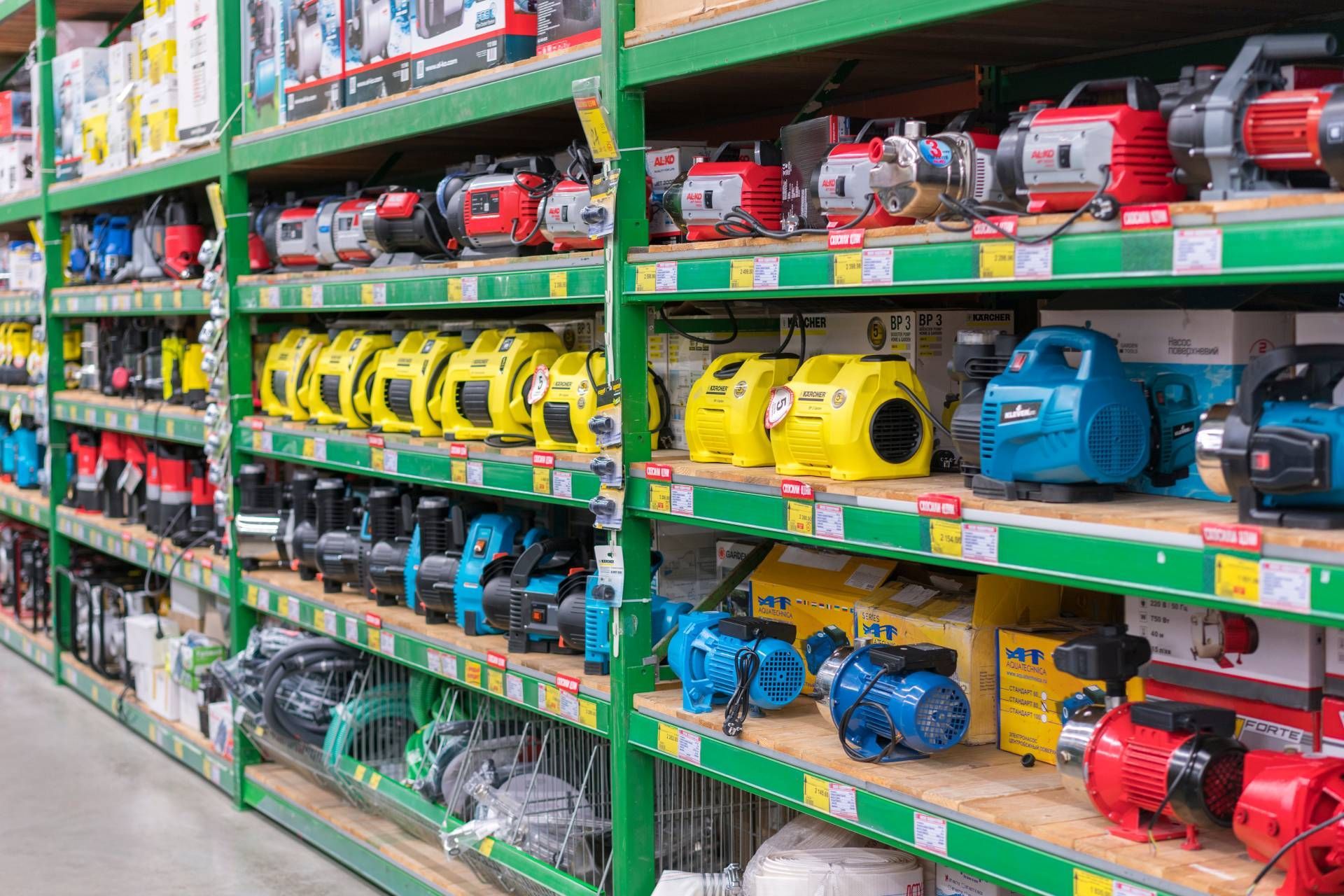 Shelves stocked with various colored power pumps in a hardware store.