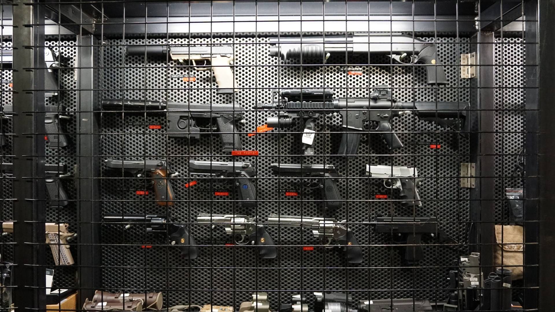 Guns displayed behind a security grate in a gun store.