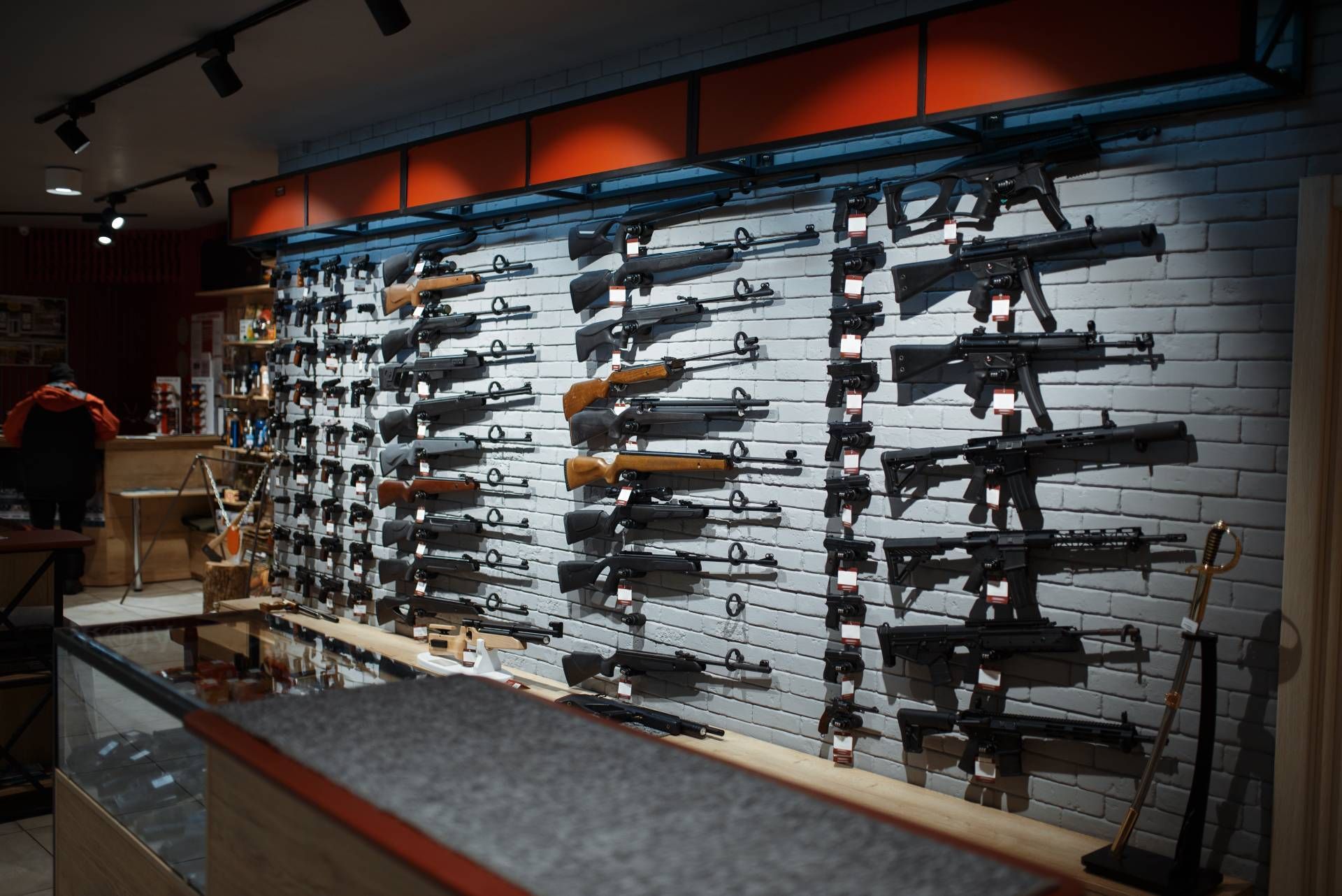 Firearms displayed on a white brick wall inside a gun shop.