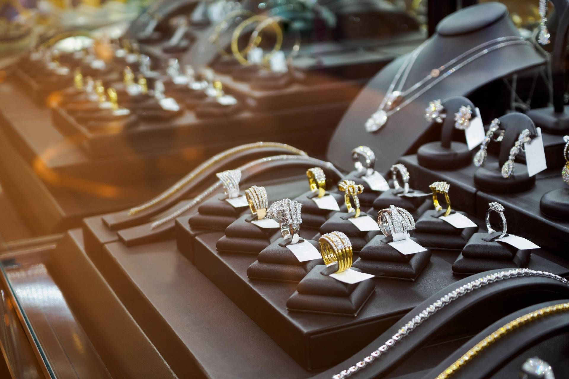 Jewelry display case, showcasing rings, necklaces, and earrings, set against a dark background.