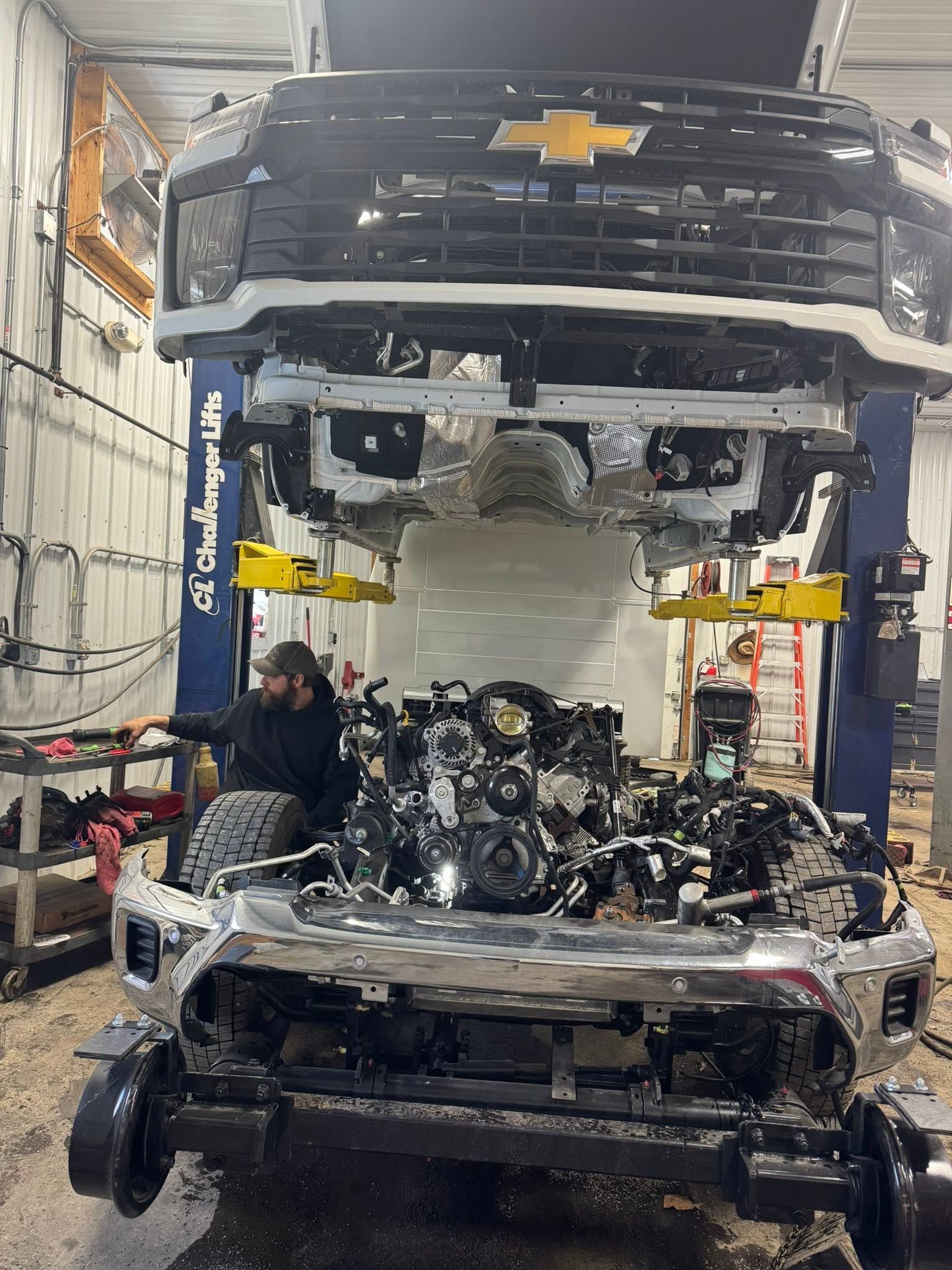 Mechanic inspecting a car engine in a bright auto repair shop with tool carts nearby