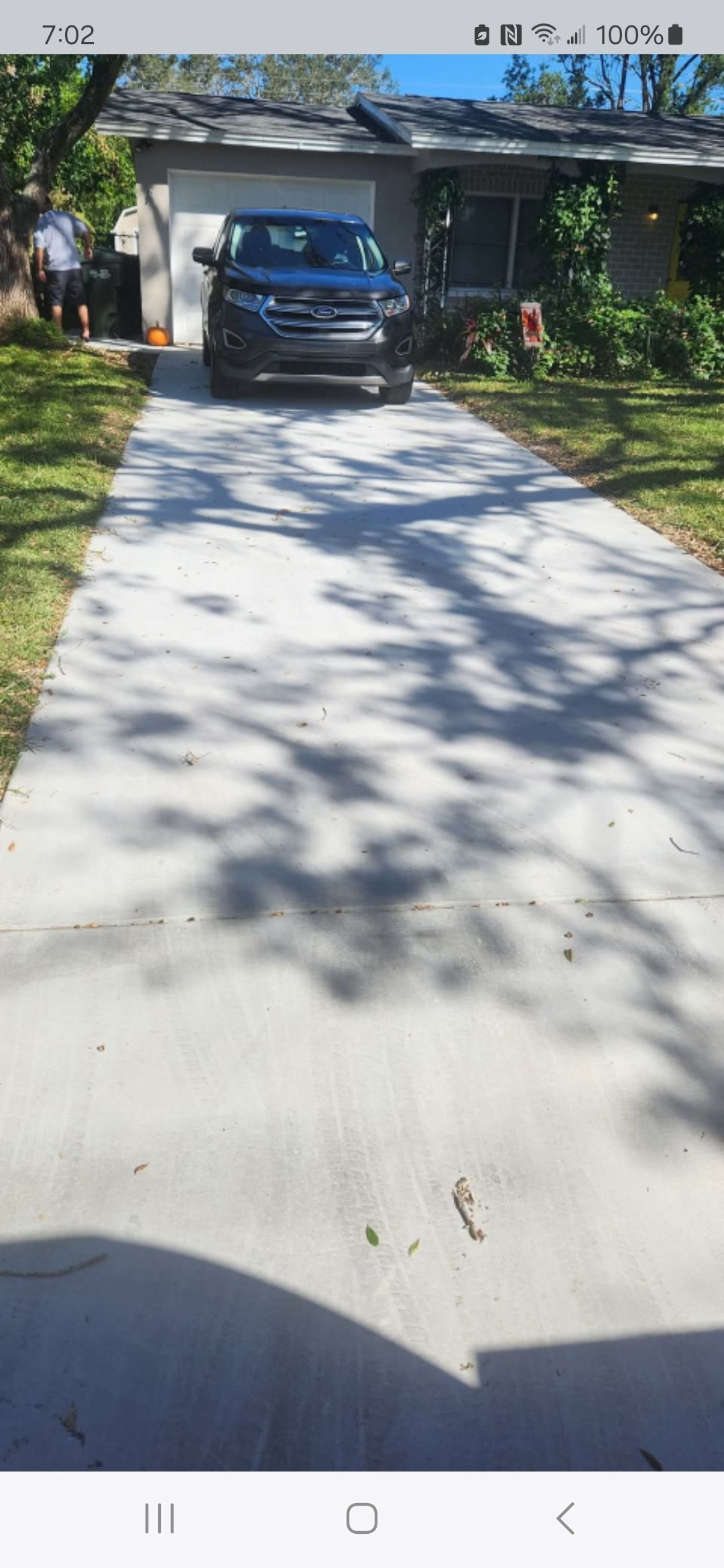 A car is parked on a concrete driveway in front of a house.