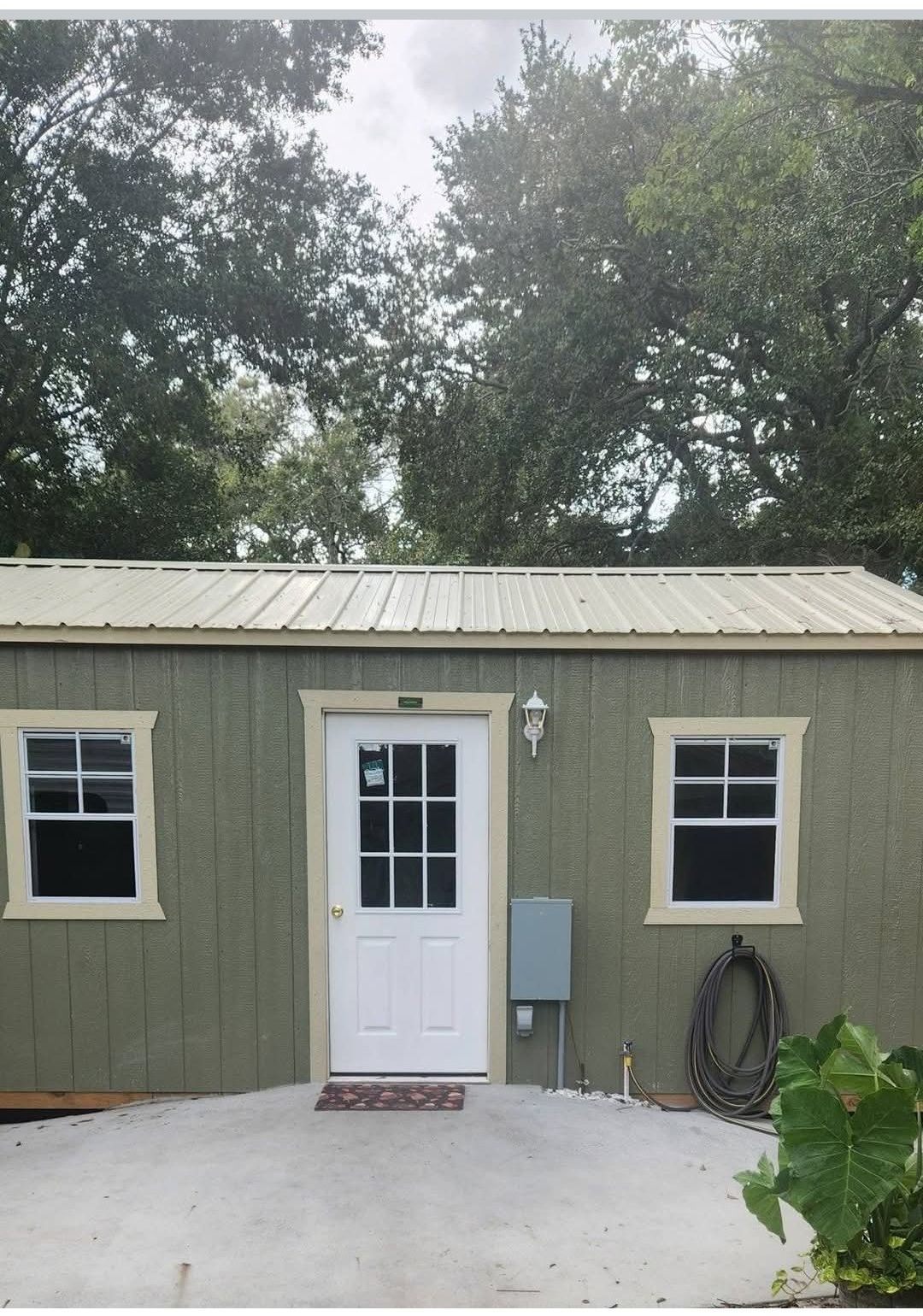 A small green house with a white door and windows.