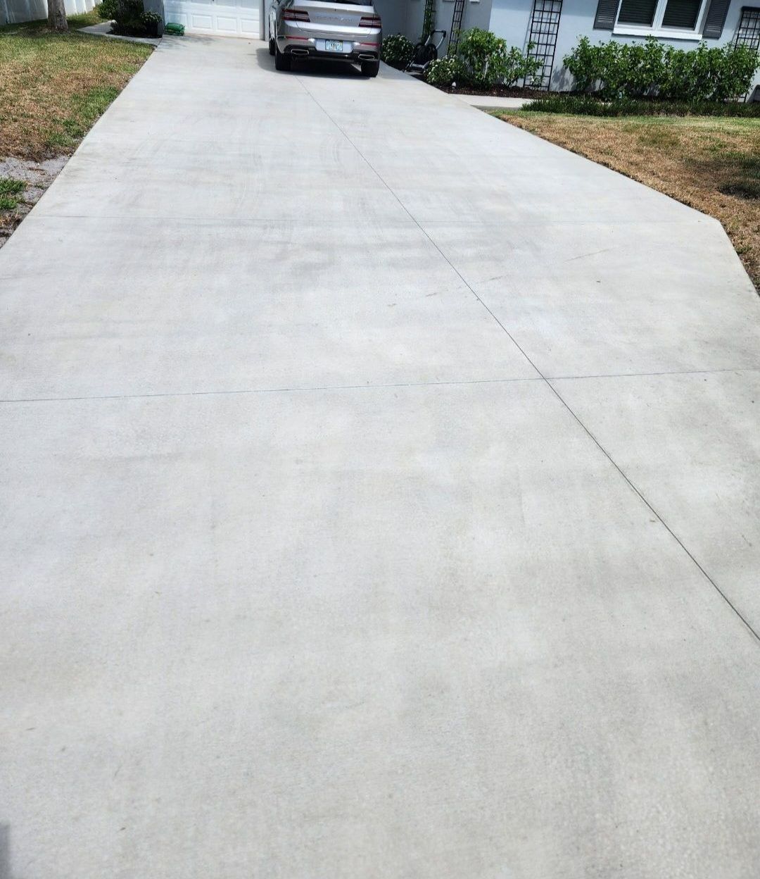 A large brick house with three garage doors and a concrete driveway.