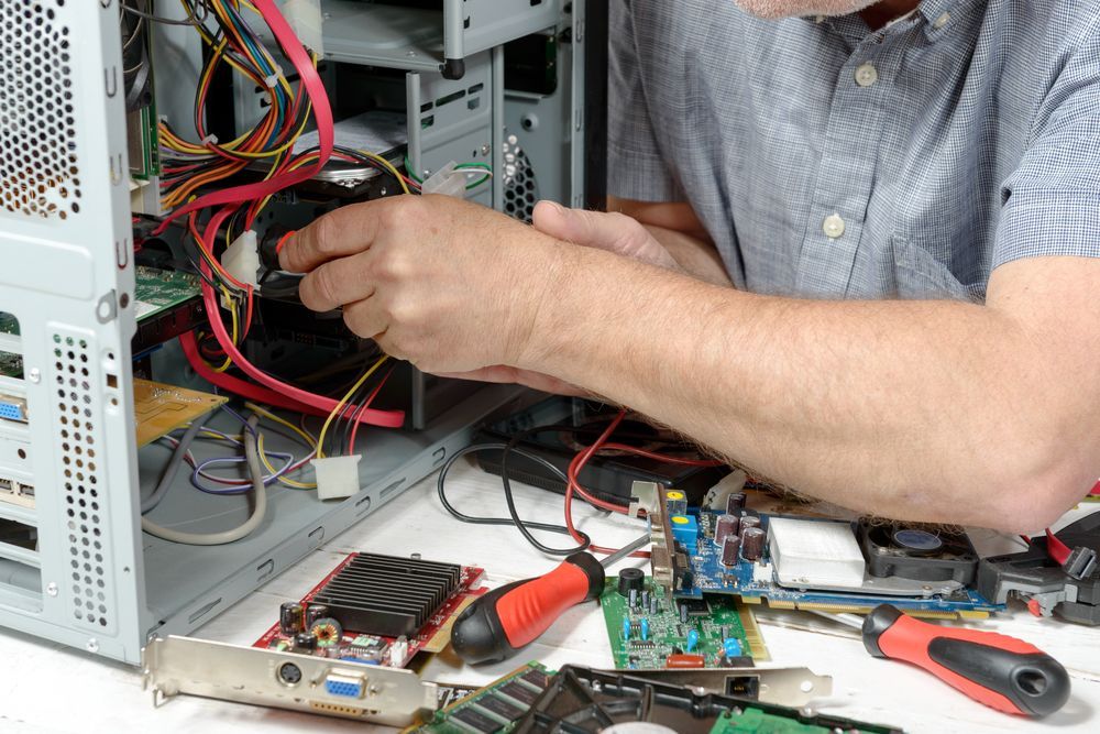 Man in Blue Shirt Working on a Desktop Computer, Surrounded by Components and Tools — Micromac Computers in Charmhaven, NSW
