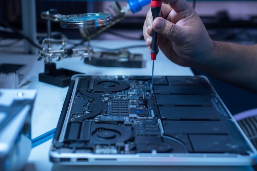 Technician repairing a laptop’s internal components with a precision screwdriver.