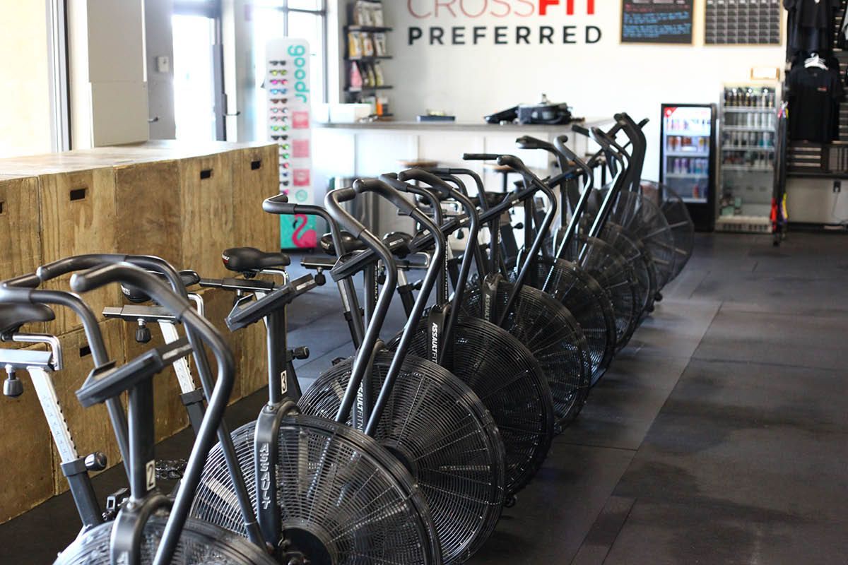 A row of exercise bikes in a gym with a sign that says crossfit preferred