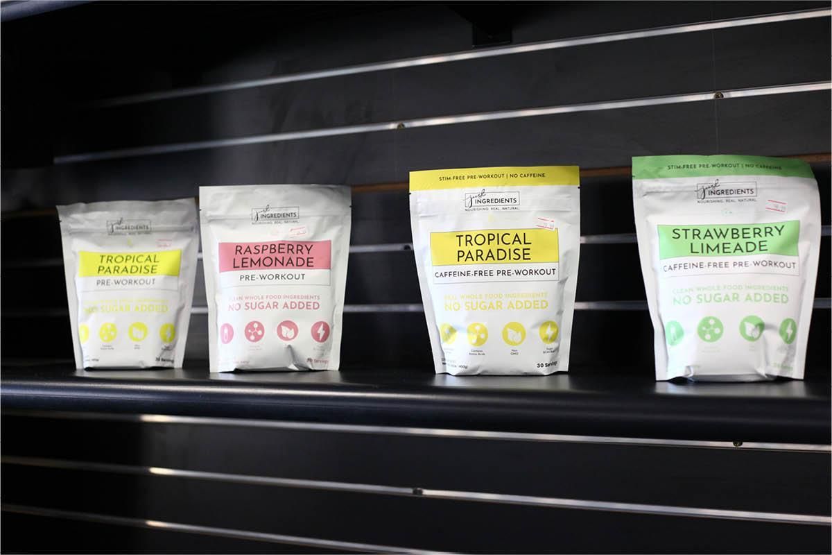 Four bags of food are lined up on a shelf.