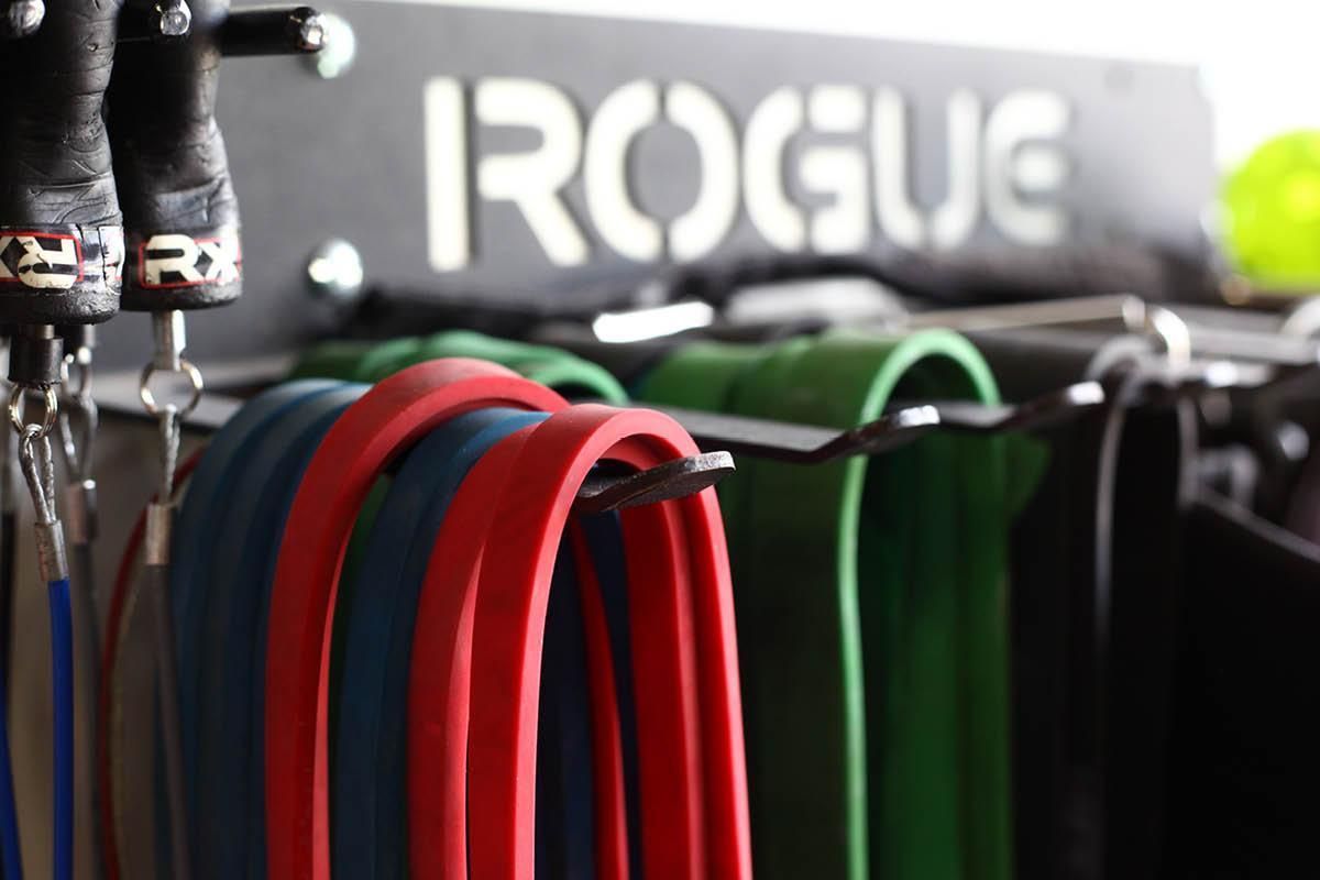 A bunch of resistance bands are hanging on a rack that says rogue