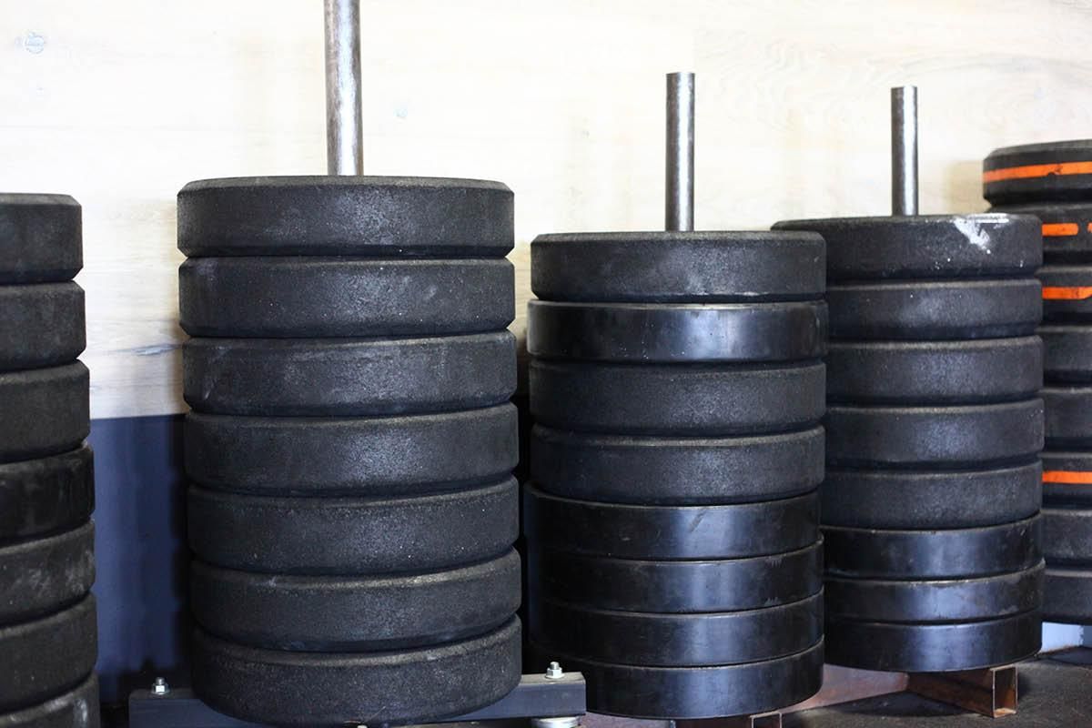 A bunch of black weights are stacked on top of each other in a gym.