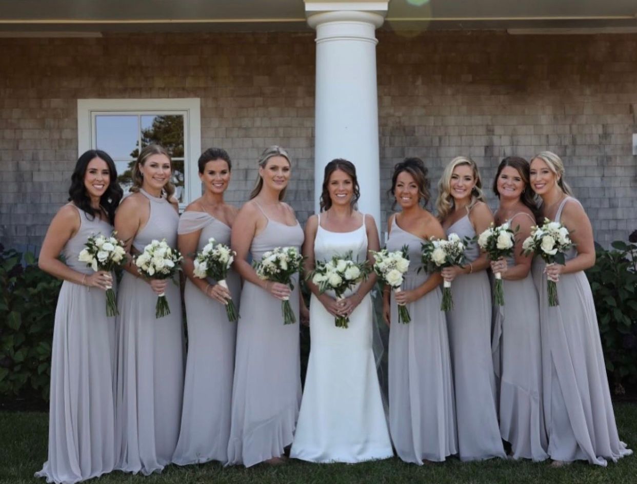 A bride and her bridesmaids are posing for a picture in front of a building.