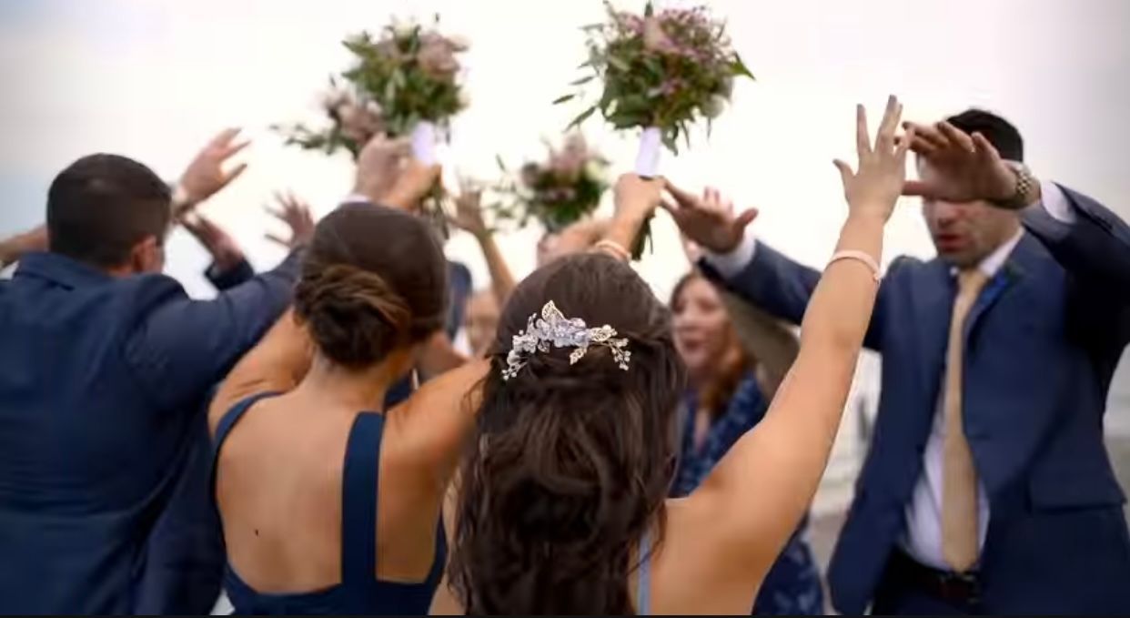 A bride and her wedding party are throwing their bouquets in the air.