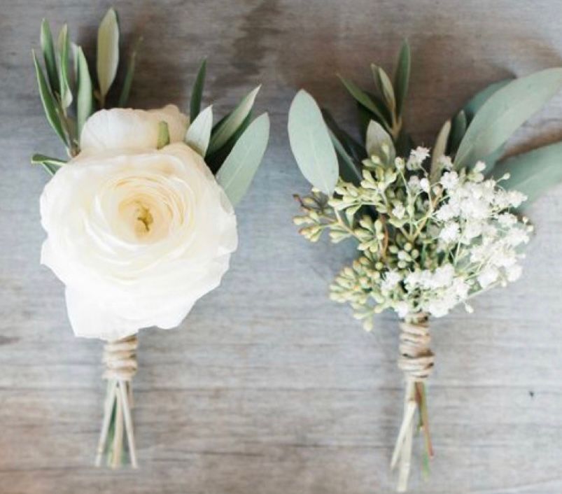 Two white flowers with green leaves on a wooden table