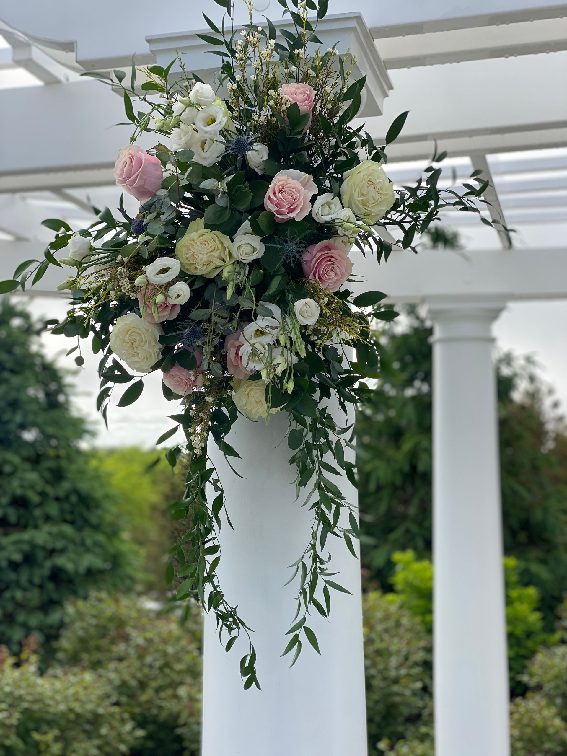 A white column with flowers hanging from it.
