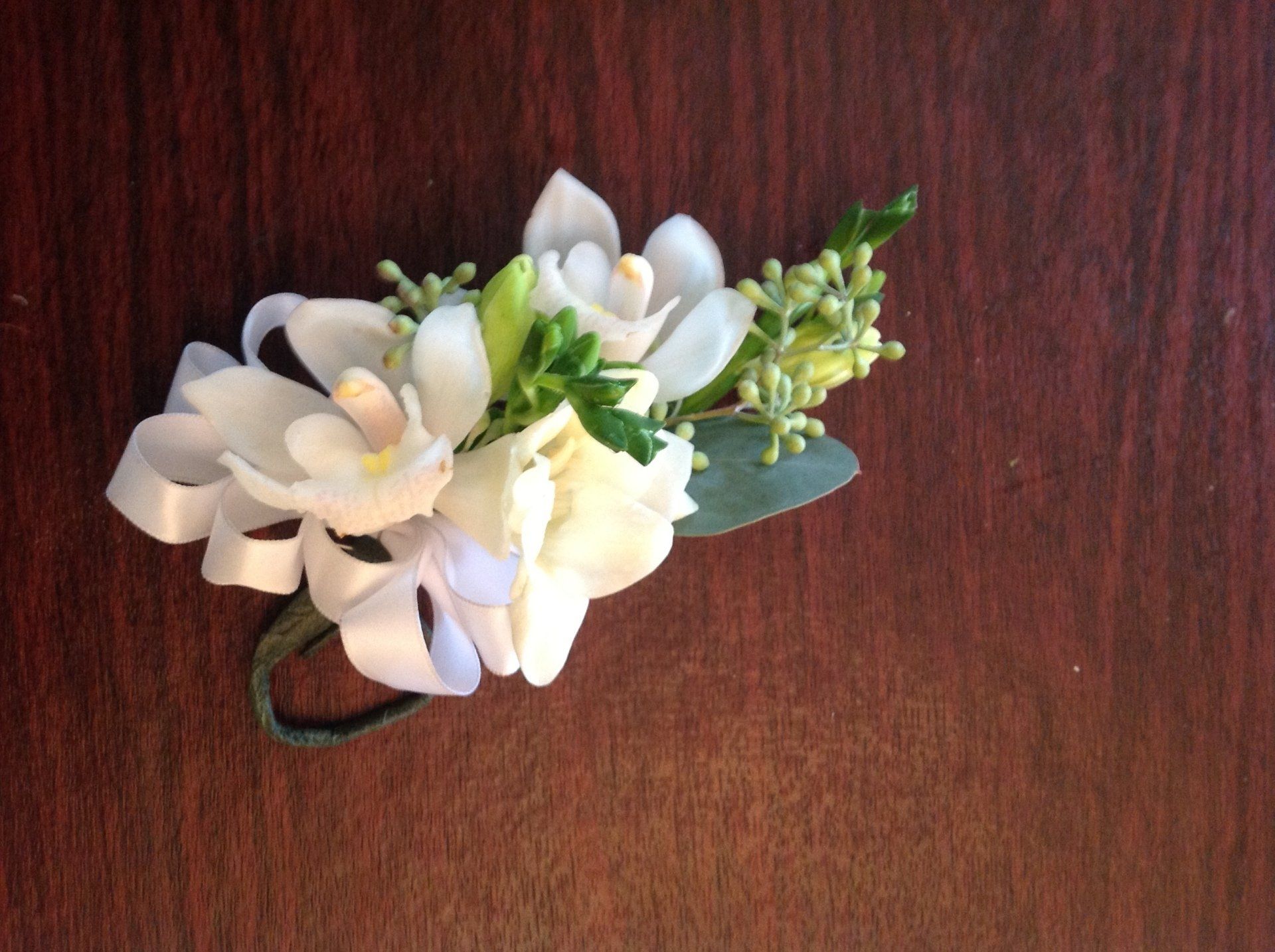 A small bouquet of white flowers is sitting on a wooden table.