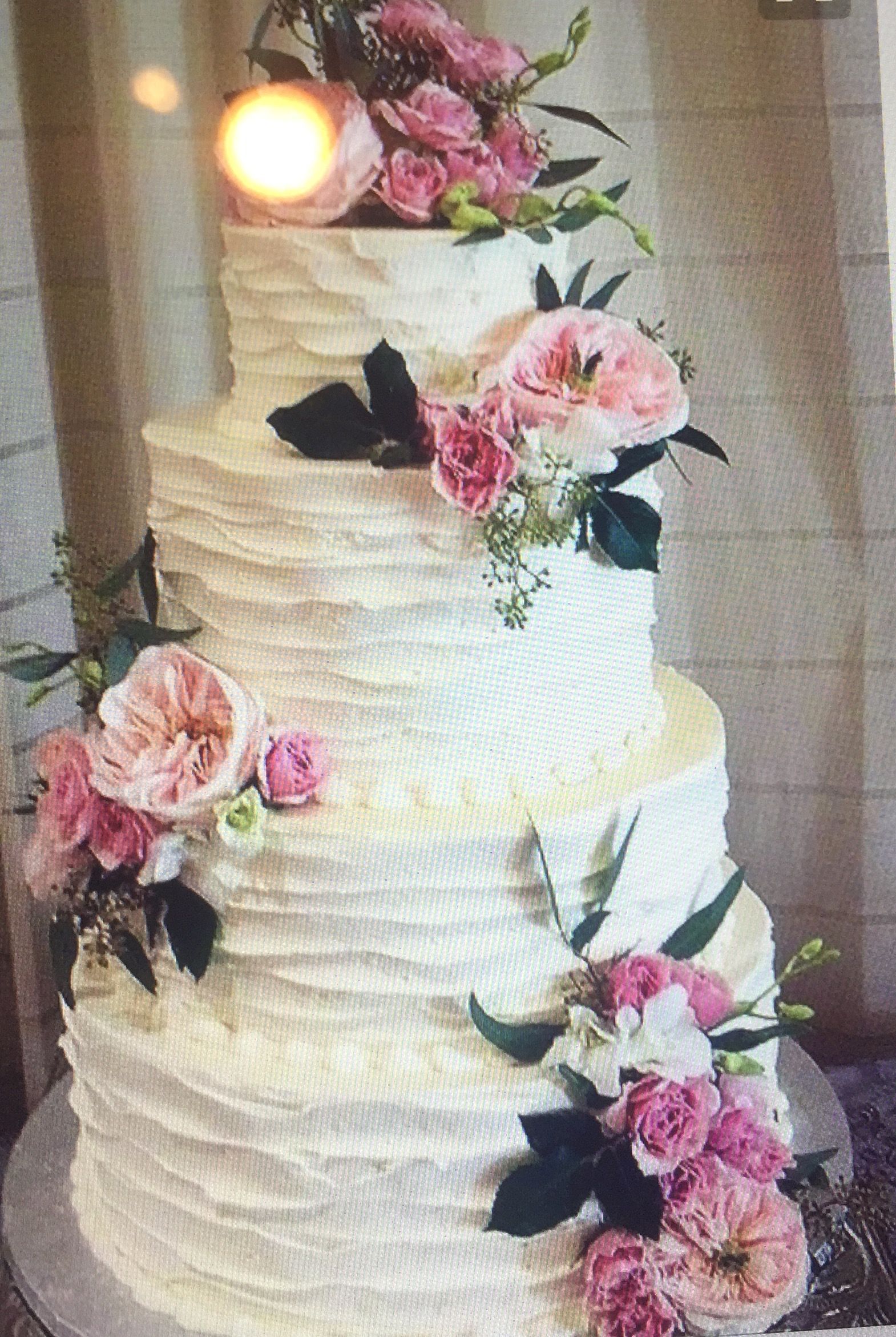 A wedding cake with pink flowers on top of it