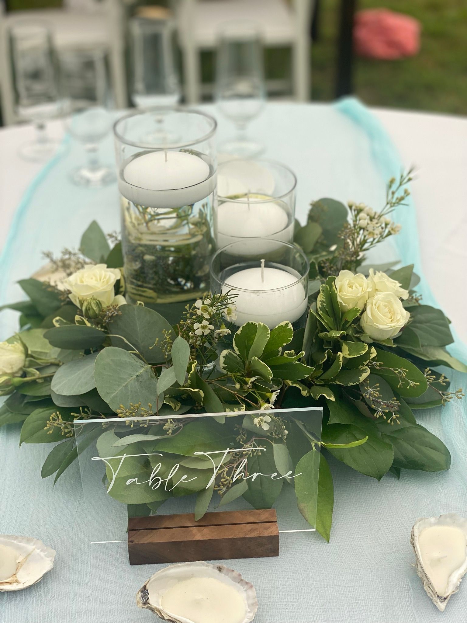 A table with a centerpiece of flowers and candles on it.