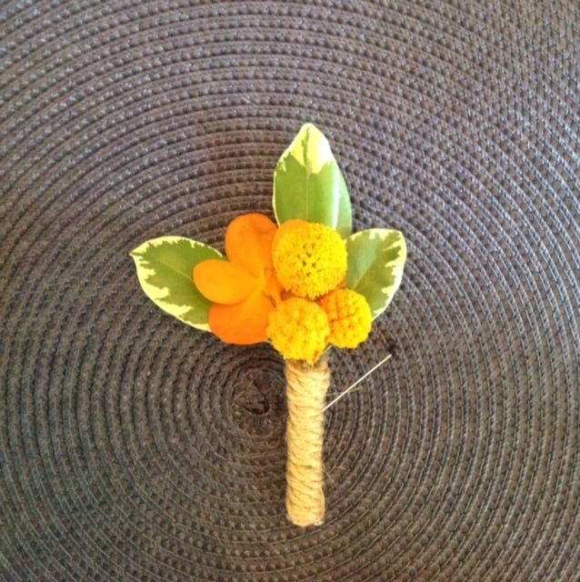 A buttonhole with yellow flowers and green leaves