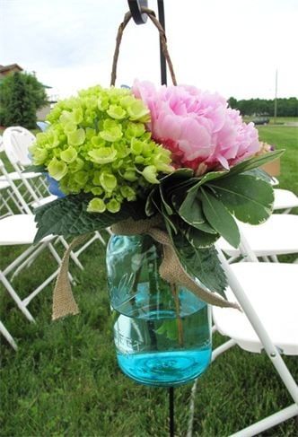 A white folding chair with a bouquet of ferns and flowers on it.