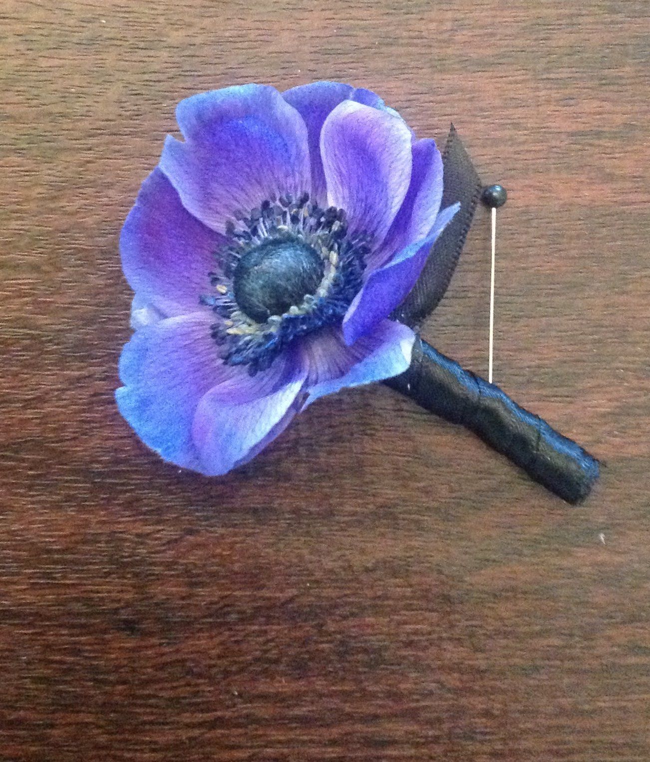 A purple flower is pinned to a wooden surface