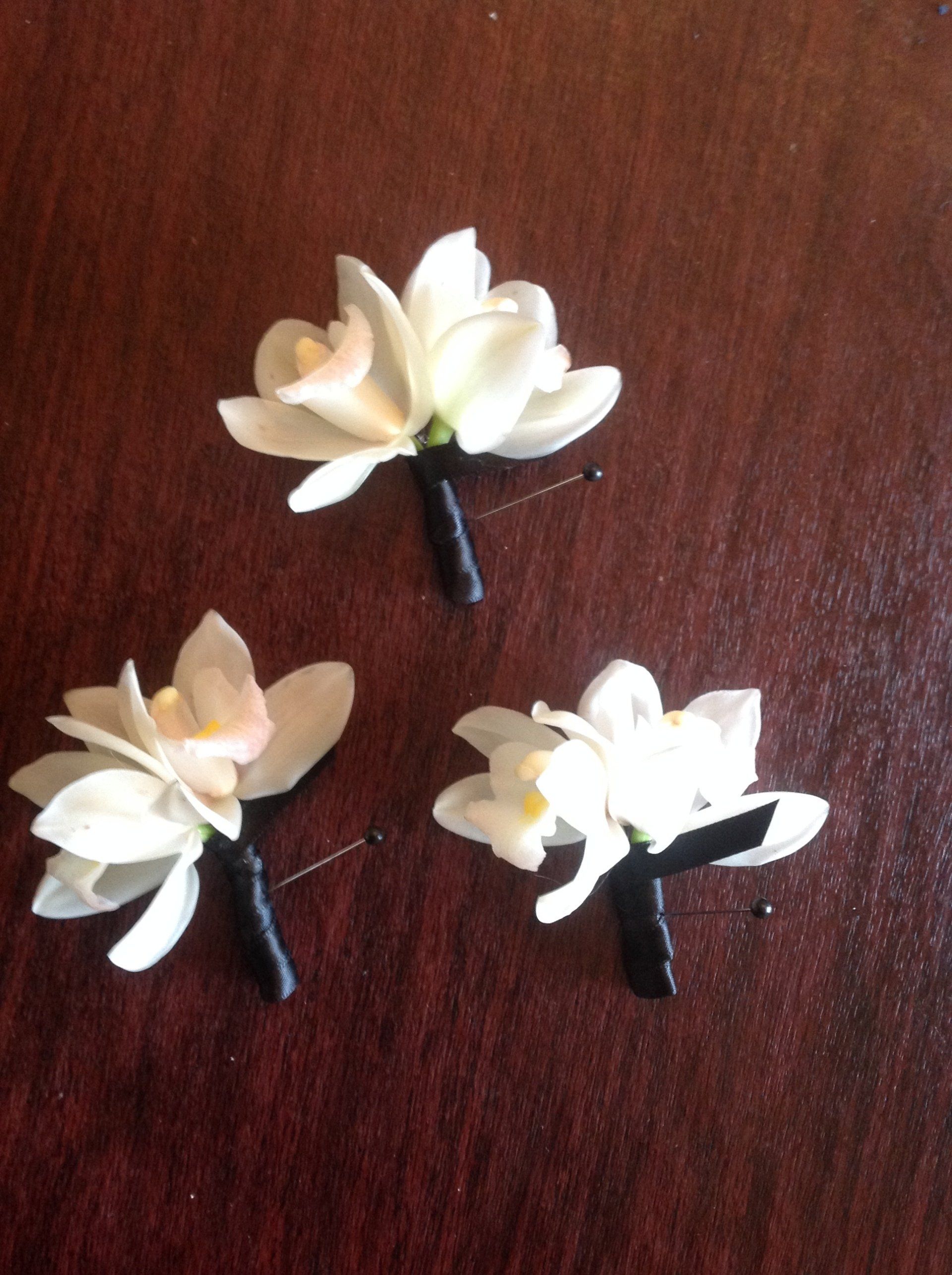 Three white flowers with black stems on a wooden table