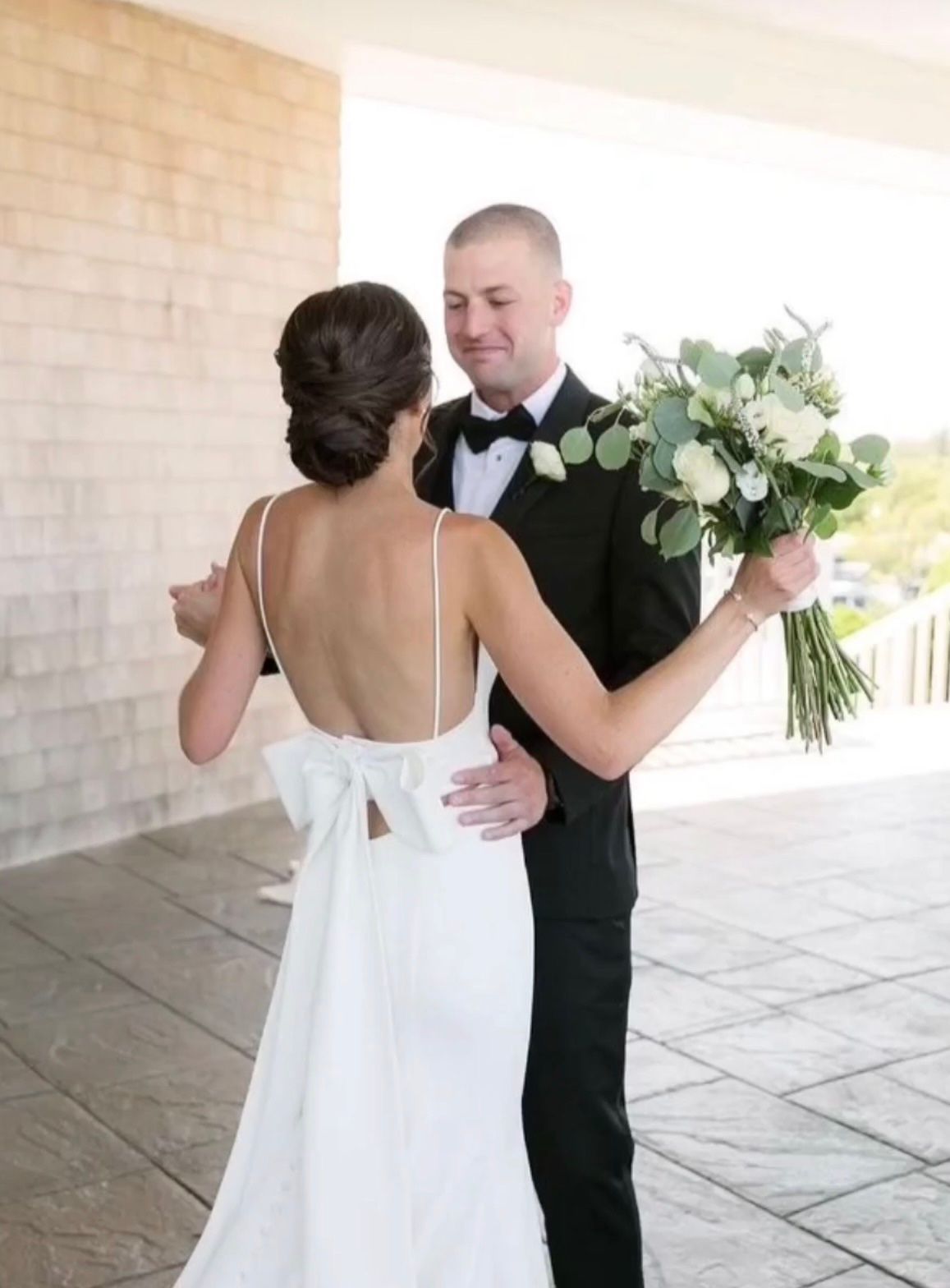 The bride is wearing a white dress and the groom is wearing a tuxedo.