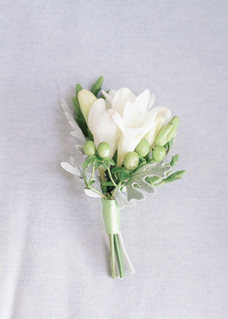 A small bouquet of white flowers and green berries on a table.