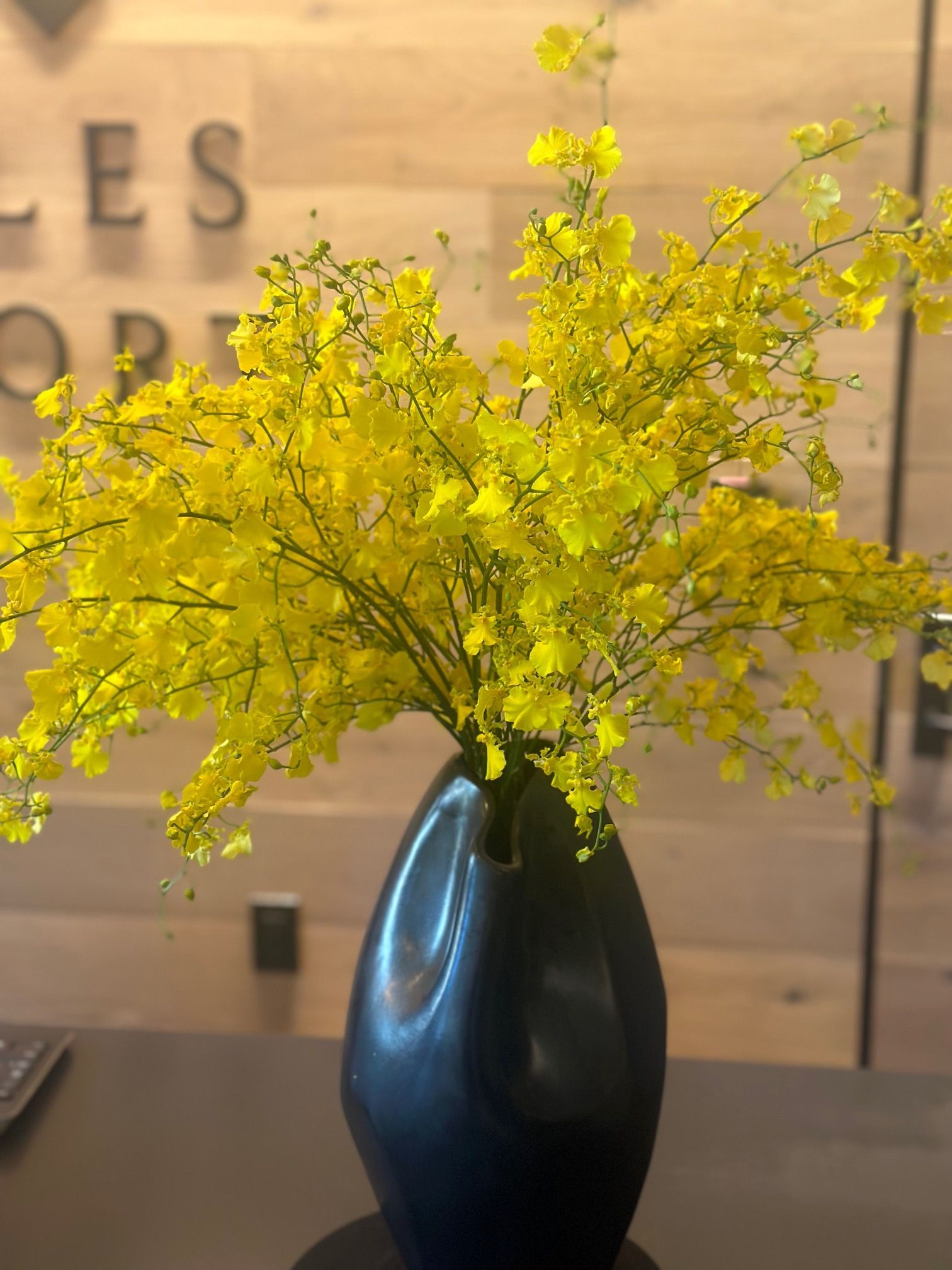 A black vase filled with yellow flowers on a table