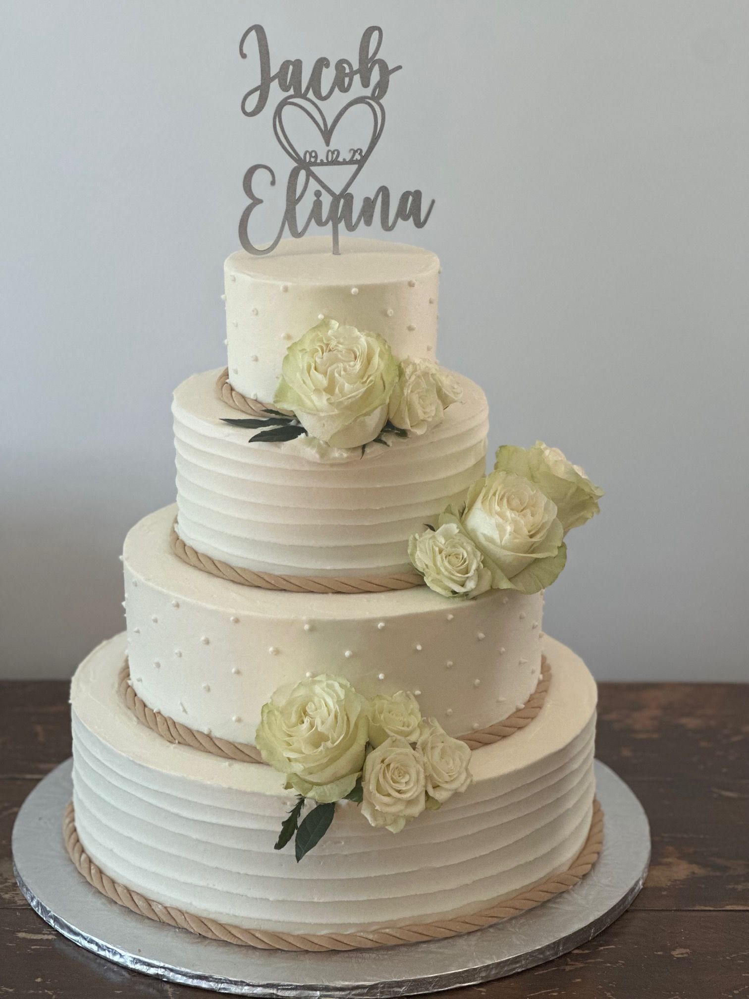 A wedding cake with a topper that says jacob and eliana
