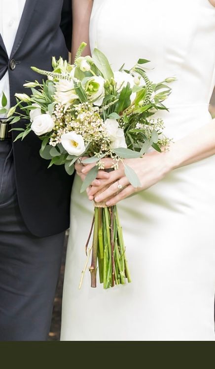 A bride in a white dress is holding a bouquet of white flowers.